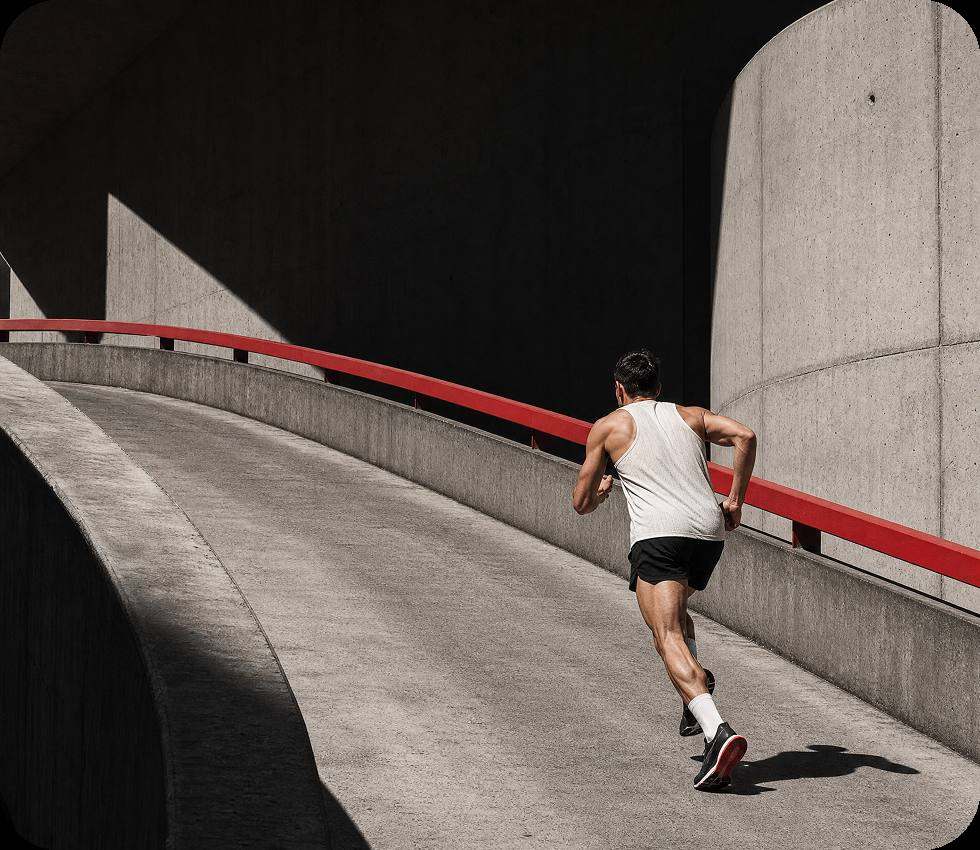 Runner climbing a concrete ramp beside a red railing